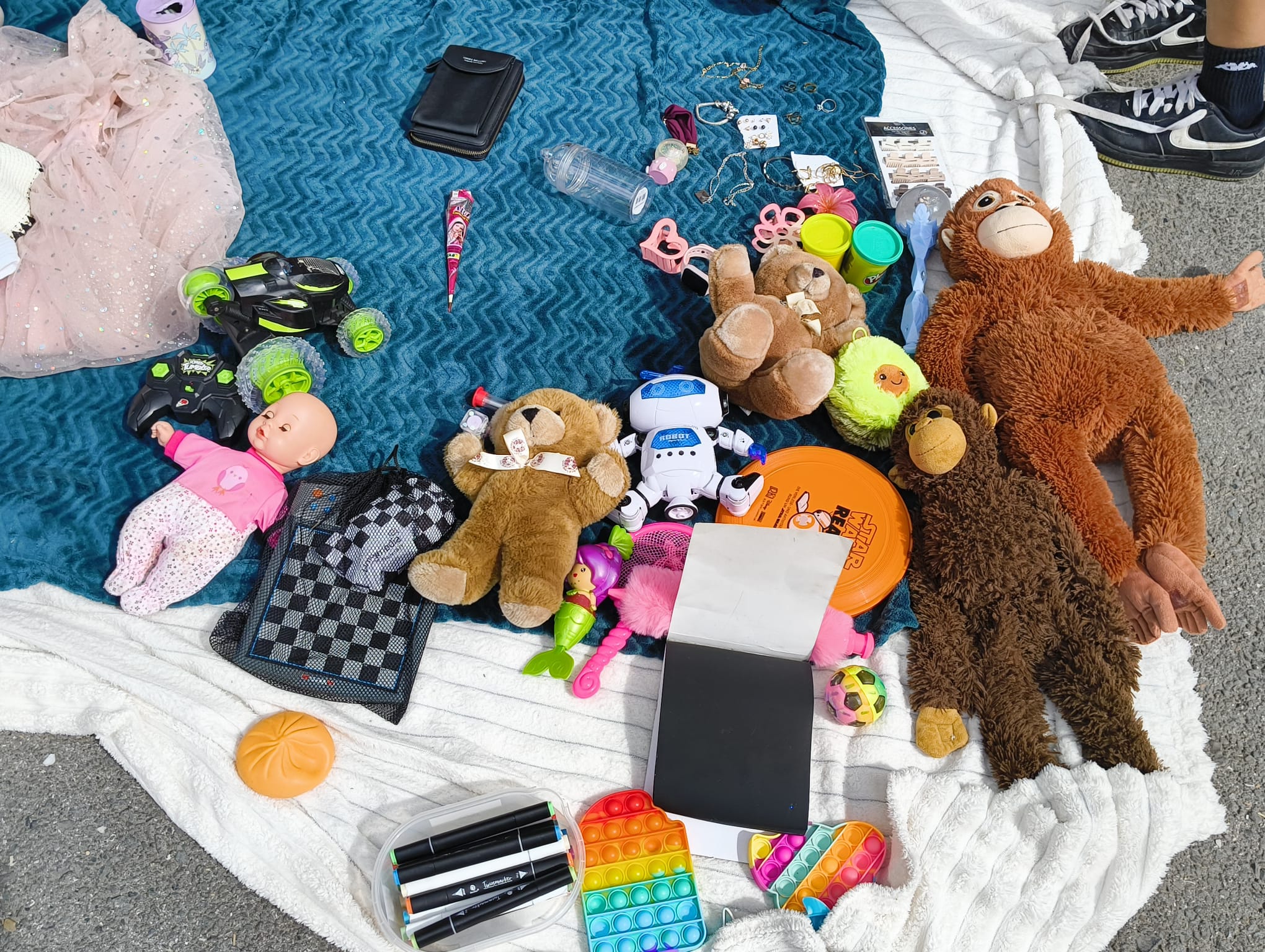 Bücher, Schmuck, Taschen und kleine Schätze auf einer Verkaufsdecke beim Kinderflohmarkt